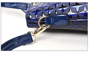 Detail of navy blue geometric embossed handbag featuring shiny finish and gold metal hook