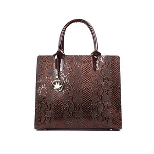Brown faux leather handbag with crocodile pattern and gold leaf pendant in front view
