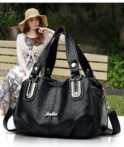 Detail of black leather handbag with silver rings and rivets on a garden bench