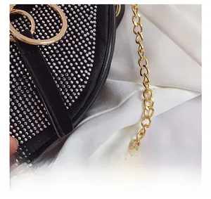 Close-up of sparkling silver rhinestones on black evening bag with gold chain link