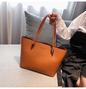 Brown leather tote bag featuring Forever Young text held by a model in home setting