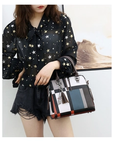 Detail of color-block tote bag with metal cat charm and tassel shown on model