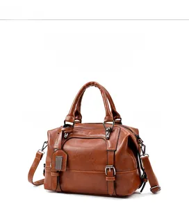 Macro detail of brown retro Boston bag showing oil leather texture and metal plate