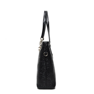 Black litchi-textured tote bag with embossed camellia flowers and smooth leather strap