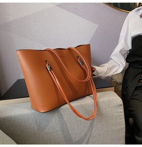Detail of caramel brown tote bag featuring Forever Young logo and smooth faux leather finish
