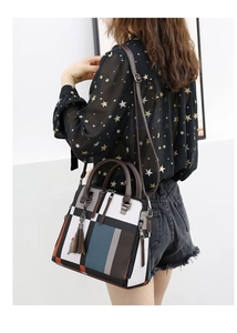 Side view of multi-color patchwork handbag with brown tassels worn by a model