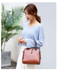 Sac à main marron avec relief crocodile et zips verticaux porté par un mannequin chic