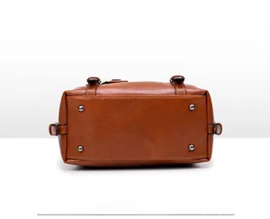 Detailed bottom view of brown faux leather handbag with four gold protective metal studs