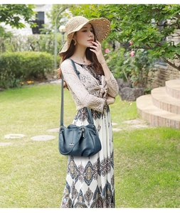Detail of dark blue faux leather shoulder bag with top handle and metal logo in a garden