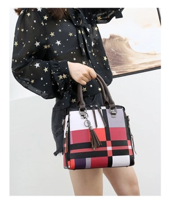 Detail of color-block plaid handbag with brown handle and elegant tassel pendant