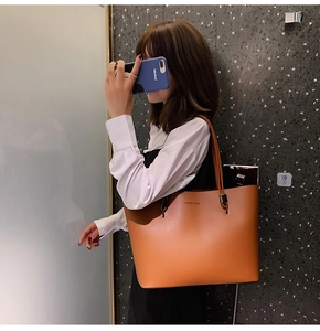 Close-up of a camel leather tote bag with Forever Young logo and long shoulder strap