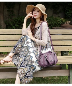 Detail of a purple leather tote bag shown on a park bench with dual handles and shoulder strap