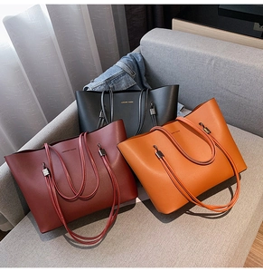 Detail of minimalist leather tote bags in black, burgundy and orange with metal hardware