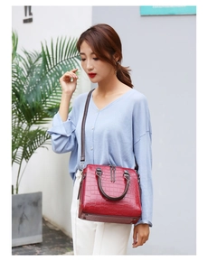 Détail du sac à main bordeaux à texture crocodile porté en bandoulière pour femme