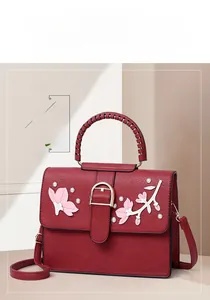 Detail of dark red handbag featuring 3D floral applique and textured faux leather finish