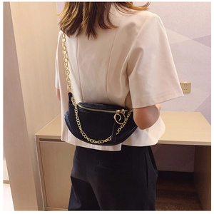 Close-up of black rhinestone crescent bag with chunky gold chain and zipper detail