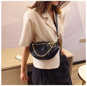 Detail of a crescent-shaped black rhinestone crossbody bag with gold chain and strap