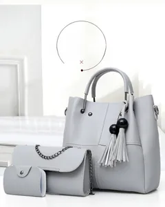 Detailed view of light grey 3-piece bag set with tassel tote, crossbody bag and pouch