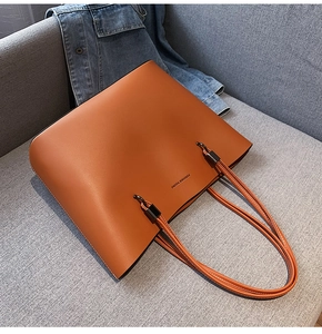 Detailed side view of a large brown leather tote bag with long shoulder straps and metal hardware