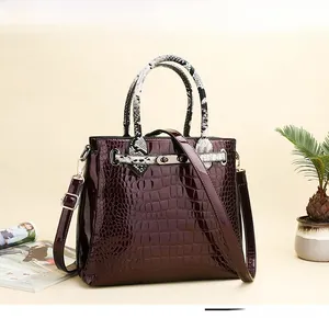 Detail of burgundy crocodile pattern handbag with snake skin texture handle and metal lock
