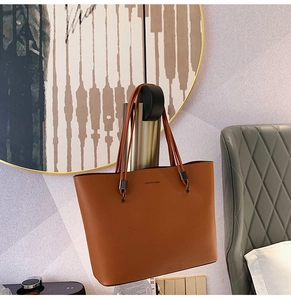 Detail of Forever Young brown tote bag featuring slender shoulder straps and metal fasteners
