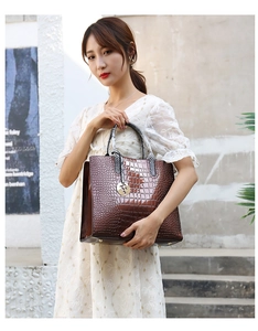 Detailed view of deep brown croc-embossed leather tote bag with gold round pendant