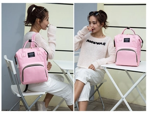 Detailed view of pink nylon multipurpose diaper backpack with top handles and front label