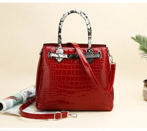 Detail of red crocodile texture handbag with snake skin handles and gold hardware accents