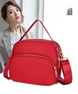 Detail of red waterproof oxford fabric crossbody bag with triple zippers and wide strap