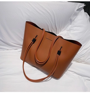 Detail showing brown PU leather tote bag with Forever Young text on white fabric