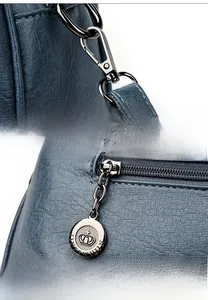 Close-up of gunmetal hardware hooks and crown logo zipper pull on navy leather bag