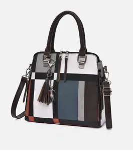 Detail view of multicolored patchwork handbag featuring leather tassels and cat pendant