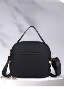 Detail of waterproof black oxford crossbody bag with golden metal zippers and top handle