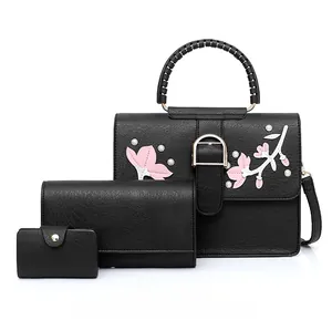 Detail of a black 3-piece bag set with floral embroidery, pearls, and woven handles