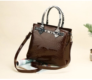 Detail of glossy brown croc-effect leather handbag with stylish snake print handle and lock