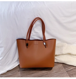 Detail of caramel brown tote bag with Forever Young embossed text and metal strap buckles