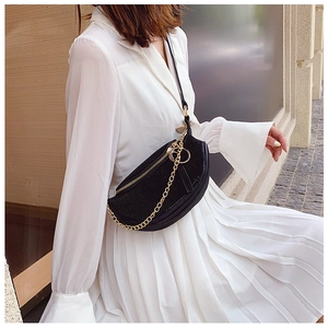 Detail view of black crescent rhinestone crossbody bag on a white dress