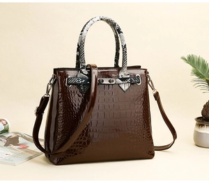 Detail of dark brown crocodile embossed tote with python print handle and metal buckle