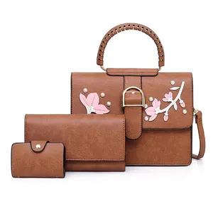 Detail view of brown PU leather 3-piece bag set with flower appliques and gold hardware