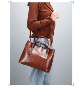 Close-up of brown vintage leather tote bag showing glossy texture and metal bottom studs