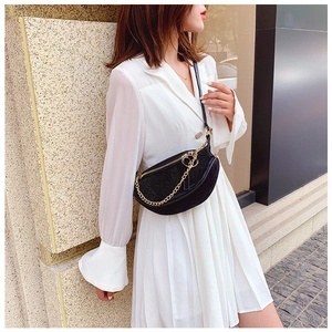 Detail of black rhinestone crescent bag with gold chain strap on a white dress