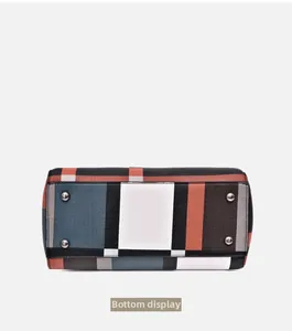 Detailed bottom view of the plaid tote bag featuring silver protective metal feet studs