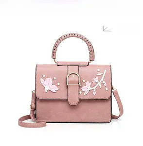 Detail of pink handbag with floral embroidery and decorative pearls on the golden buckle
