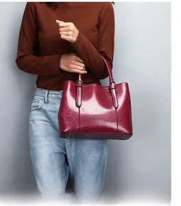 Detail of wine red glossy leather handbag featuring metal rivets on bottom base
