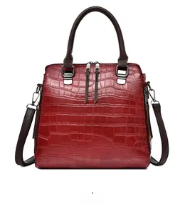 Détail du sac à main rouge texture crocodile avec ferrures argentées et bandoulière