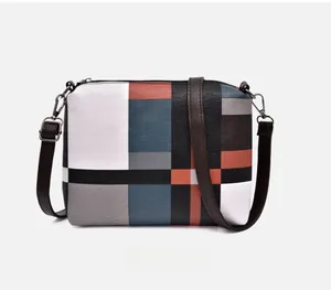 Detailed view of colorful patchwork shoulder bag with brown strap and metal zipper