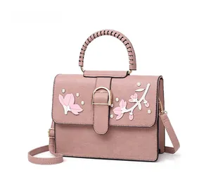 Detail of pink PU leather handbag with floral embroidery and white pearl accents