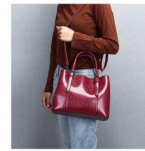 Detail of burgundy glossy patent leather tote with round handles and adjustable strap
