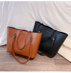 Detail of tan and black faux leather tote bags featuring Forever Young text and metal hardware