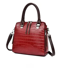 Vue détaillée du sac à main rouge foncé motif crocodile avec anses marron et détails argentés